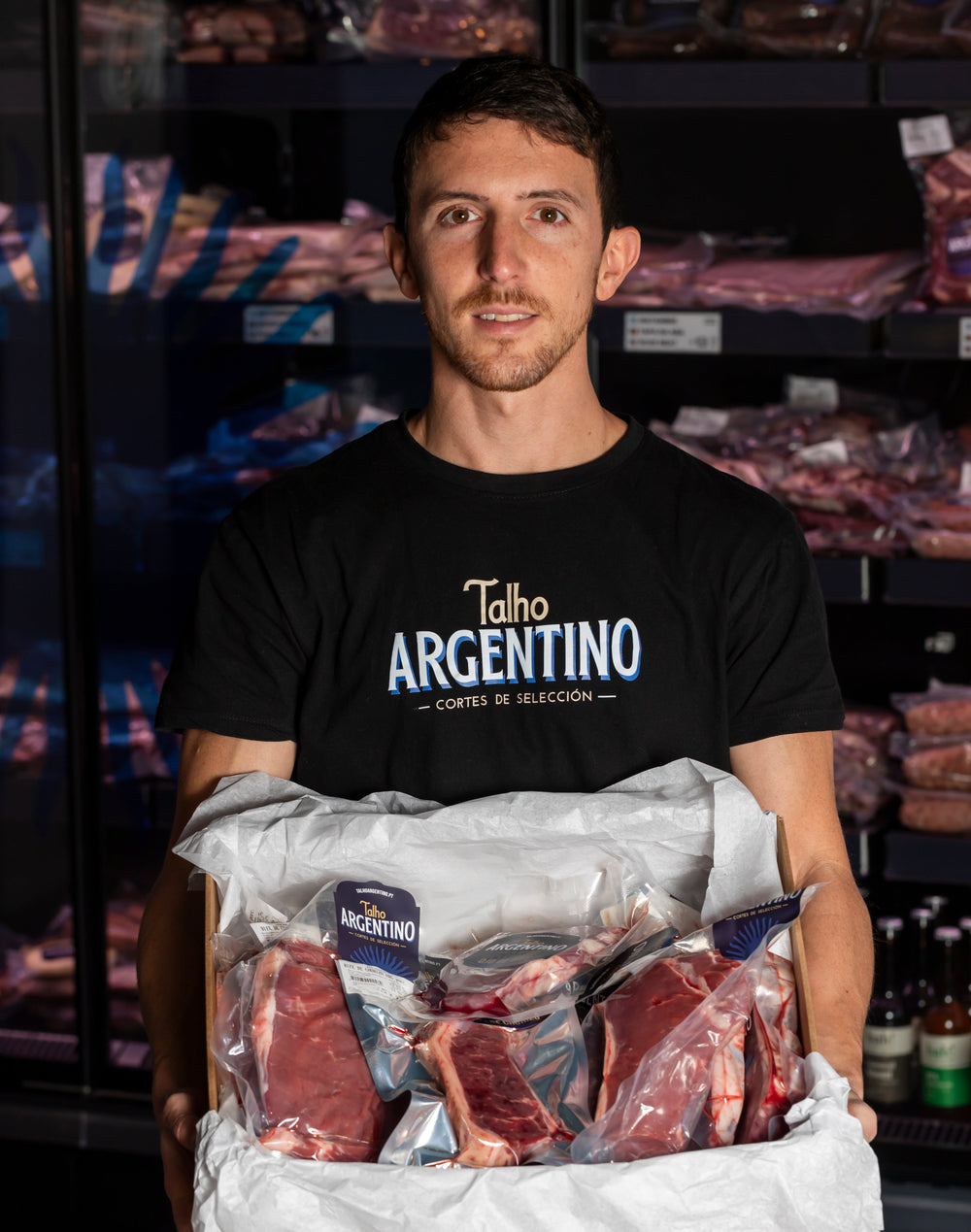 Persona con maglietta Talho Argentino che tiene una scatola di tagli confezionati sottovuoto